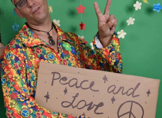 Hipiu persirengęs vaikinas su plakatu „Peace and love